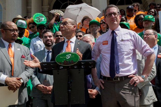 Queens Public Library President Dennis Walcott, accompanied by DC 37 Executive Director Henry Garrido, left, and Queens Library Guild Local 1321 President John Hyslop, speaks about the need for additional funding for the city’s three public library systems during a May 25 news conference and rally. Photo: Mike Lee